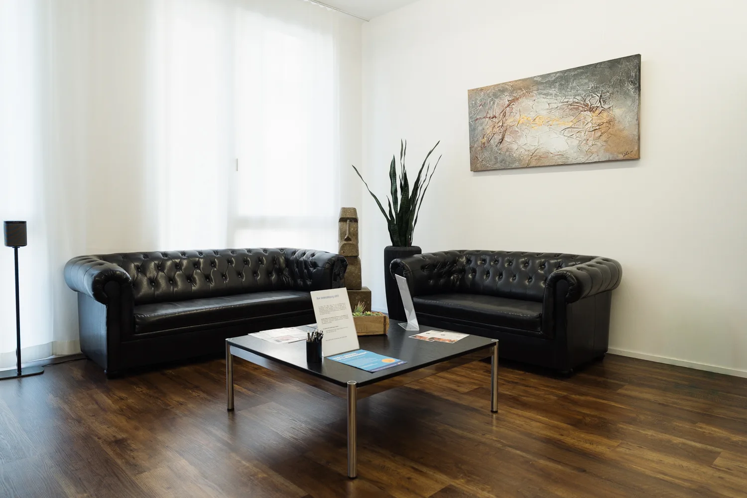 Wartebereich mit zwei schwarzen Ledersofas und Salontisch
